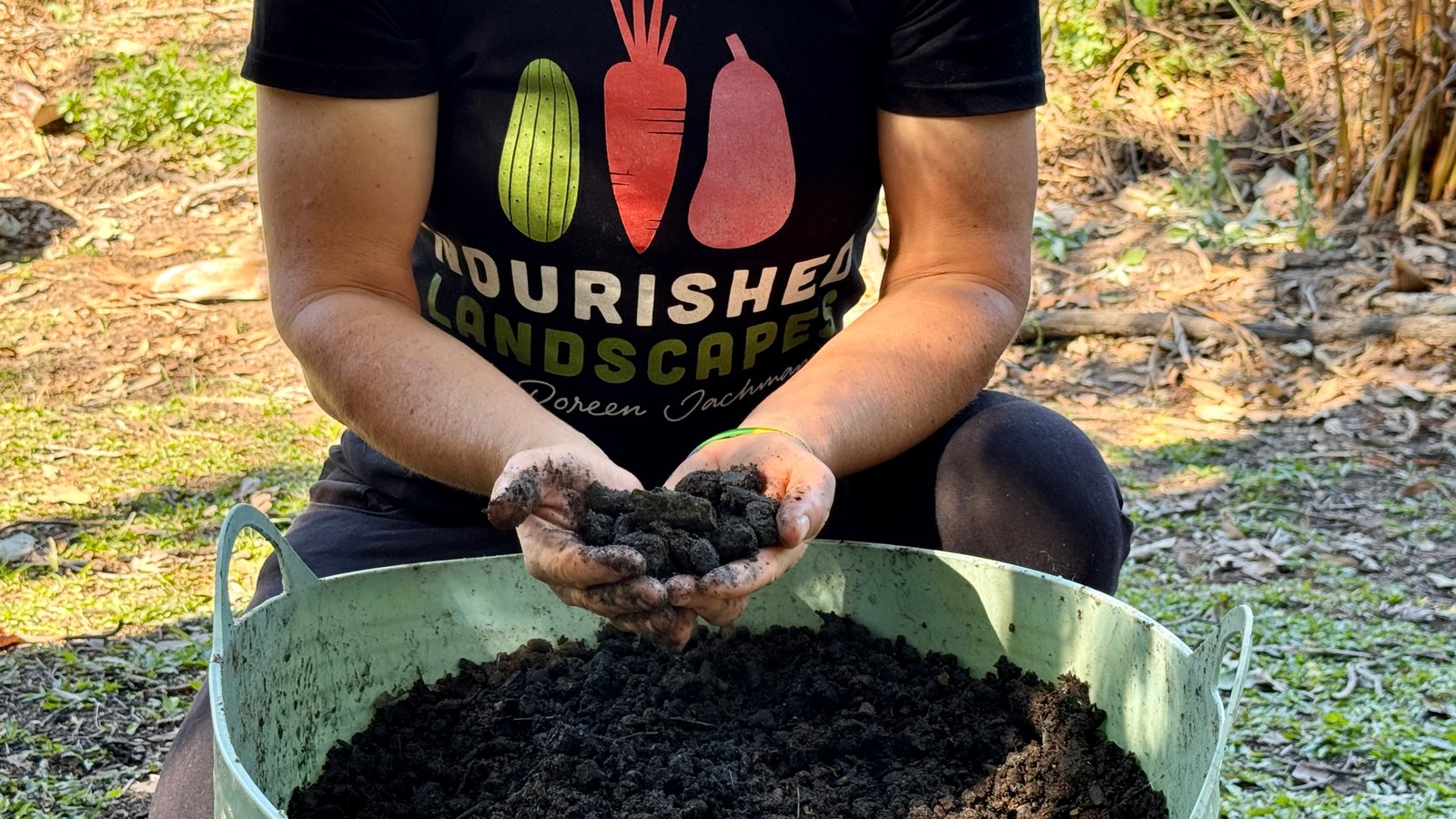 Hands mixing organic biochar into garden soil